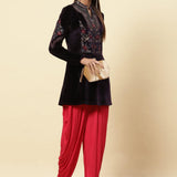 The woman is posing with Velvet Flared Tunic from Lakshita, red patiala, and a clutch 