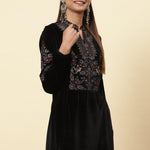 LakshitaÃ¢â‚¬â„¢s elegant velvet kurti is represented by a model with colourful floral patterns, and gold dori highlights.