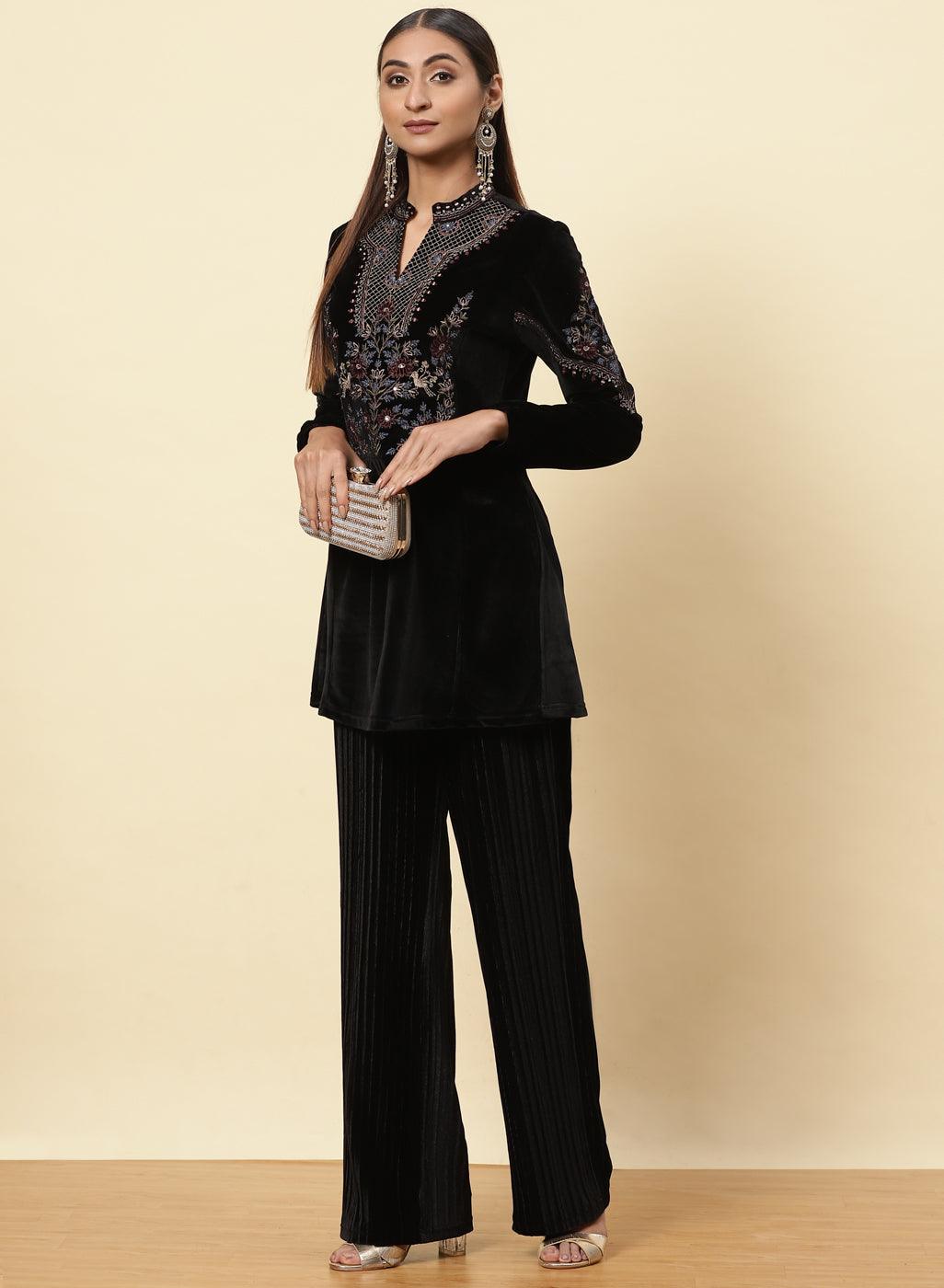 The picture shows a lady wearing a Charcoal Black Velvet Tunic with black trousers, holding a clutch