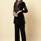 The picture shows a lady wearing a Charcoal Black Velvet Tunic with black trousers, holding a clutch