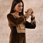 The girl is adoring the beautiful Yoke Zari Embroidery of the Golden Velvet Kurta set