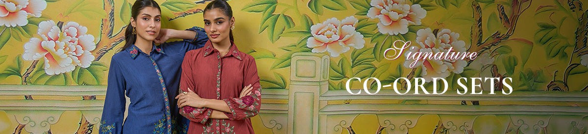 A woman in Lakshita pastel blue co-ord set with floral cutwork, walking through a lush garden under soft sunlight