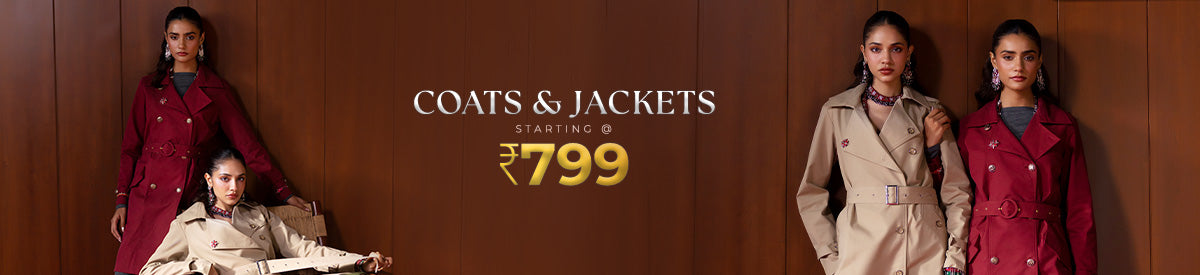 Three women in cozy winter coats and gloves enjoying snowy vibes outside a cabin — Coats & Jackets winter edit