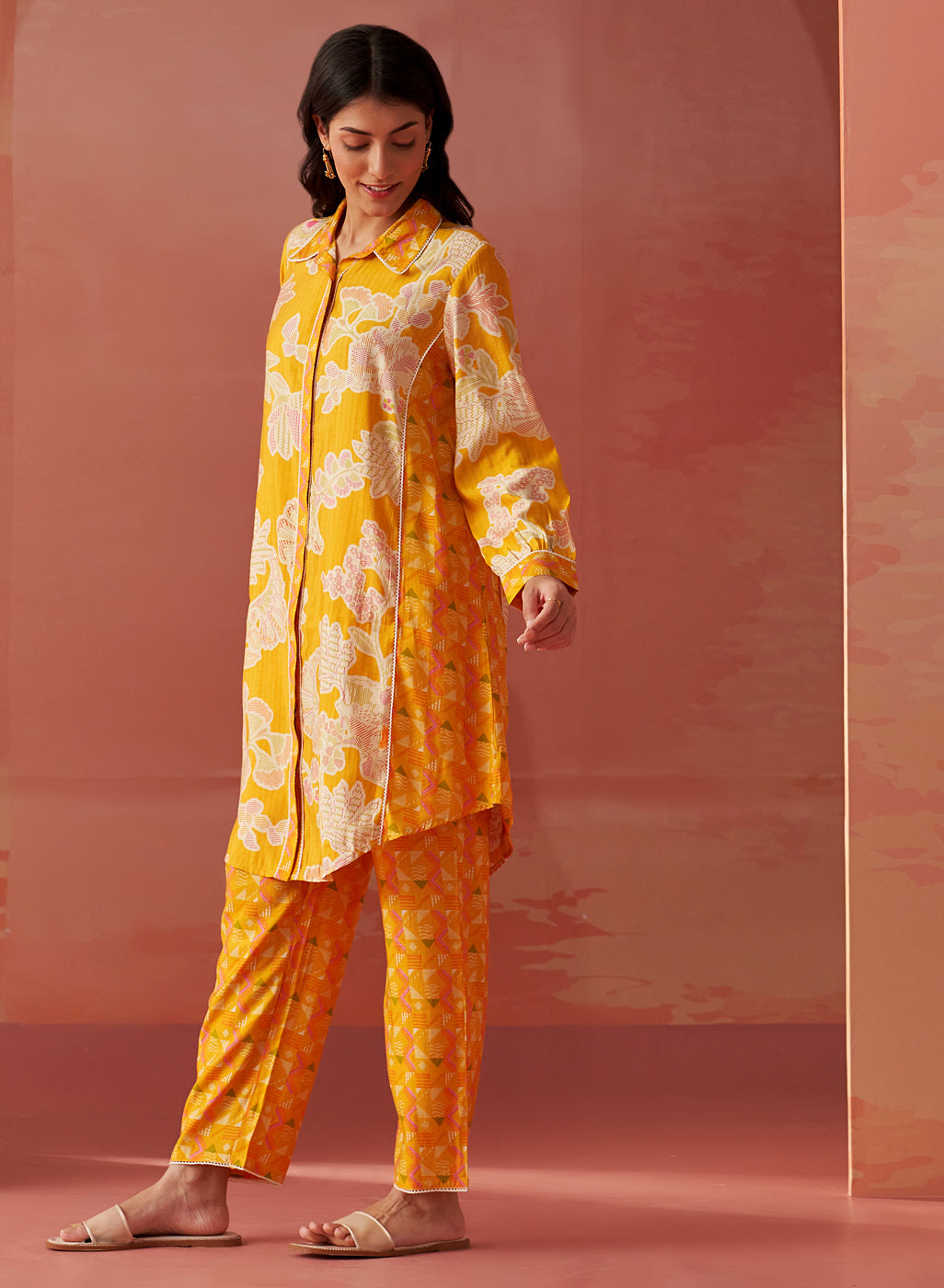 Angled profile of yellow floral printed Chanderi co-ord set for women with long collared kurta and straight printed pants.