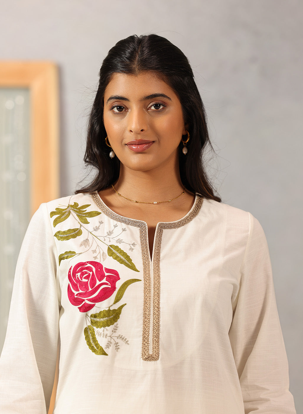 Detailed view of Lakshita Ulfat Ivory Kurta highlighting pink floral chest embroidery and zari-trimmed neckline.