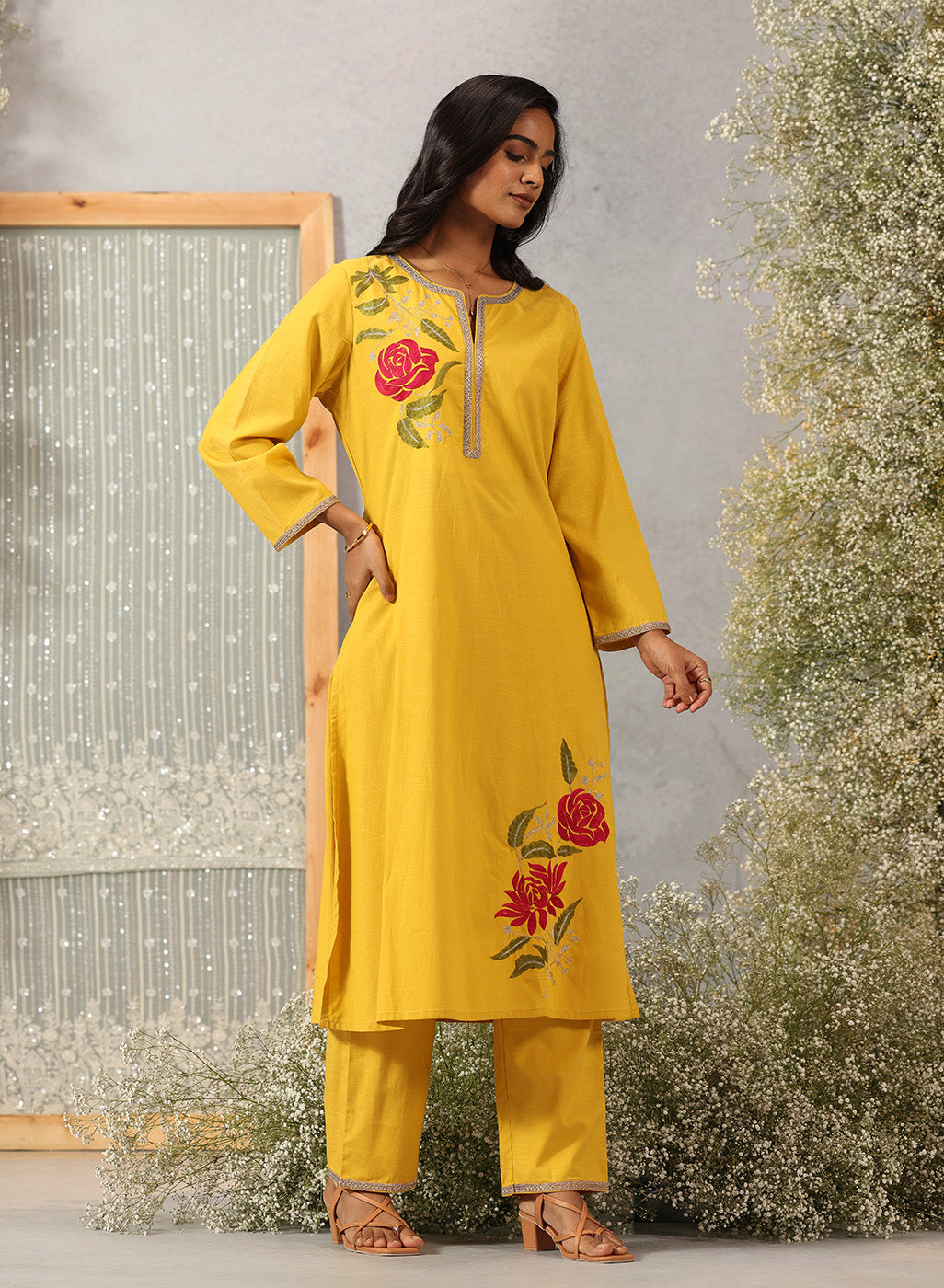 Model in Ulfat Yellow Kurta Set by Lakshita showcasing silk thread red rose motifs on one side chest and lower hem of kurta.