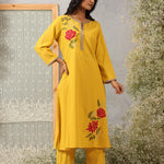 Model in Ulfat Yellow Kurta Set by Lakshita showcasing silk thread red rose motifs on one side chest and lower hem of kurta.
