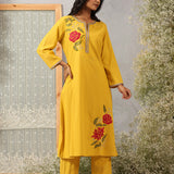 Model in Ulfat Yellow Kurta Set by Lakshita showcasing silk thread red rose motifs on one side chest and lower hem of kurta.