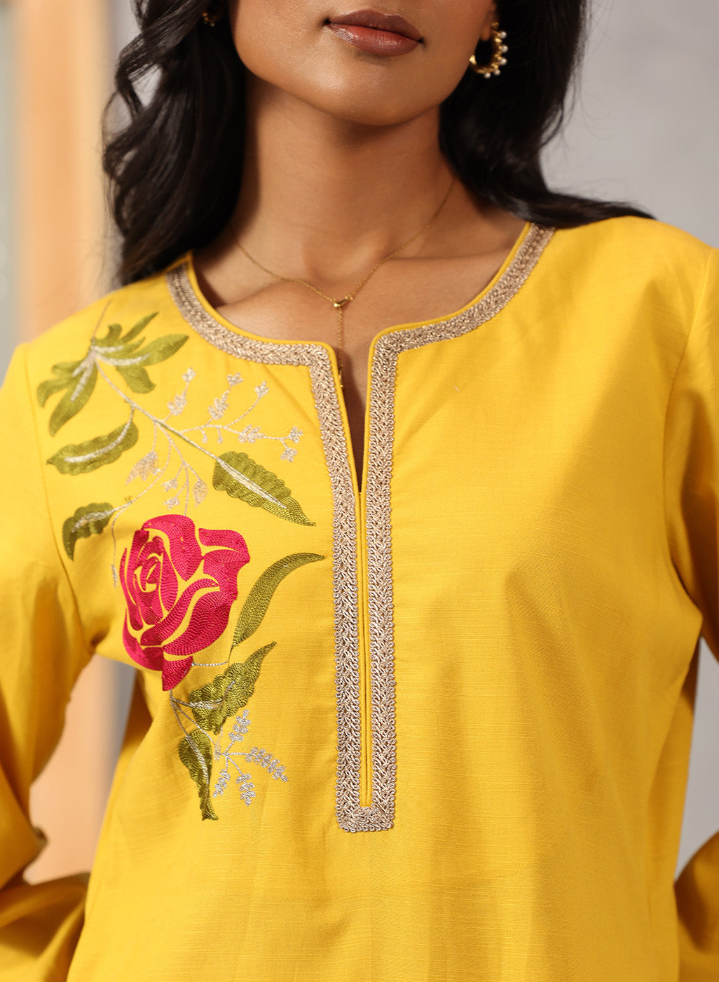 Close-up of chest detail on Lakshita Ulfat Yellow Kurta featuring red silk thread rose motif and zari lace neckline.
