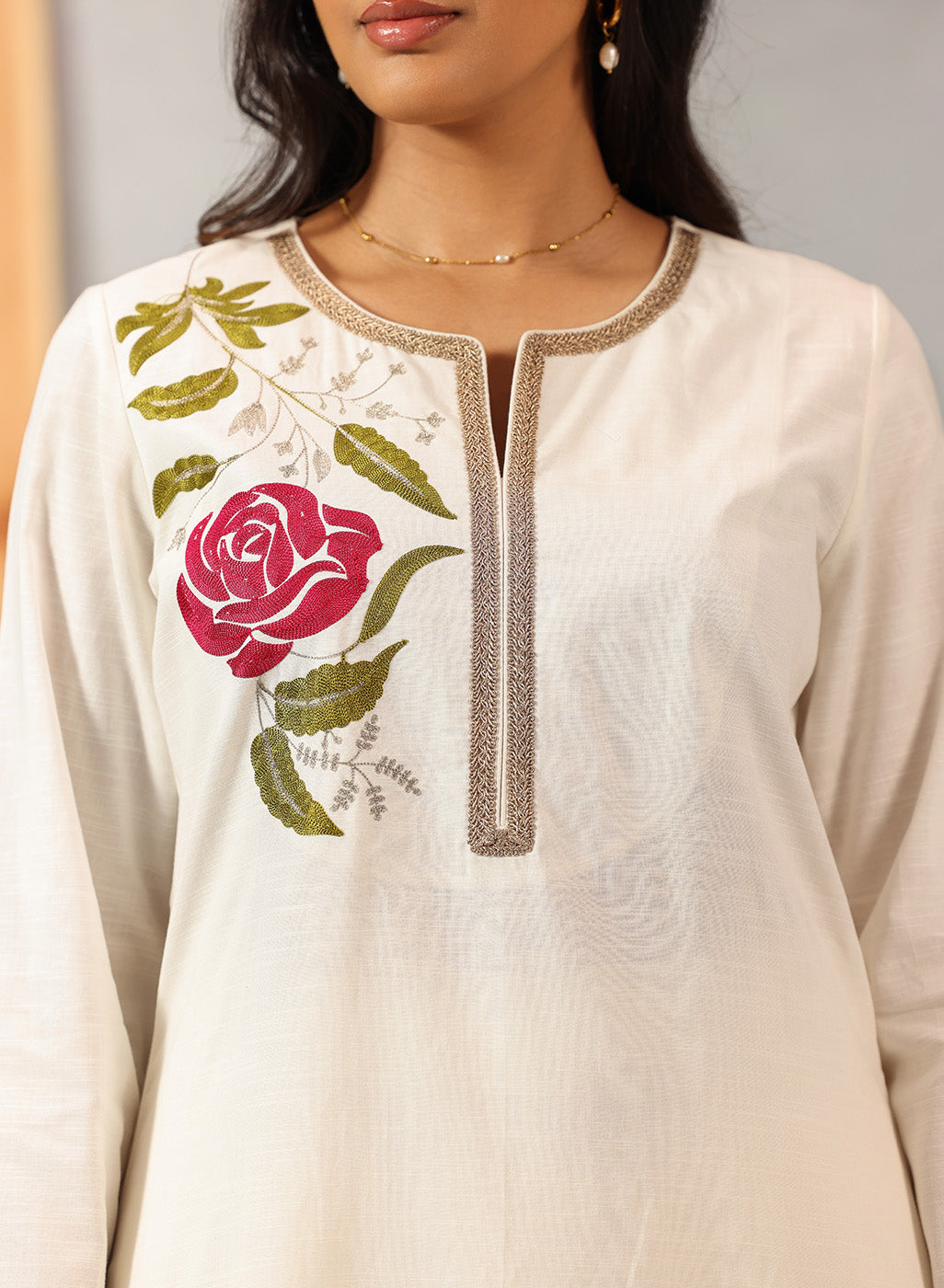 Zoomed-in chest and neck shot of Ulfat Kurta Set with soft pink rose threadwork and fine zari lace detailing on ivory base.