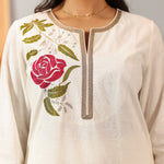 Zoomed-in chest and neck shot of Ulfat Kurta Set with soft pink rose threadwork and fine zari lace detailing on ivory base.
