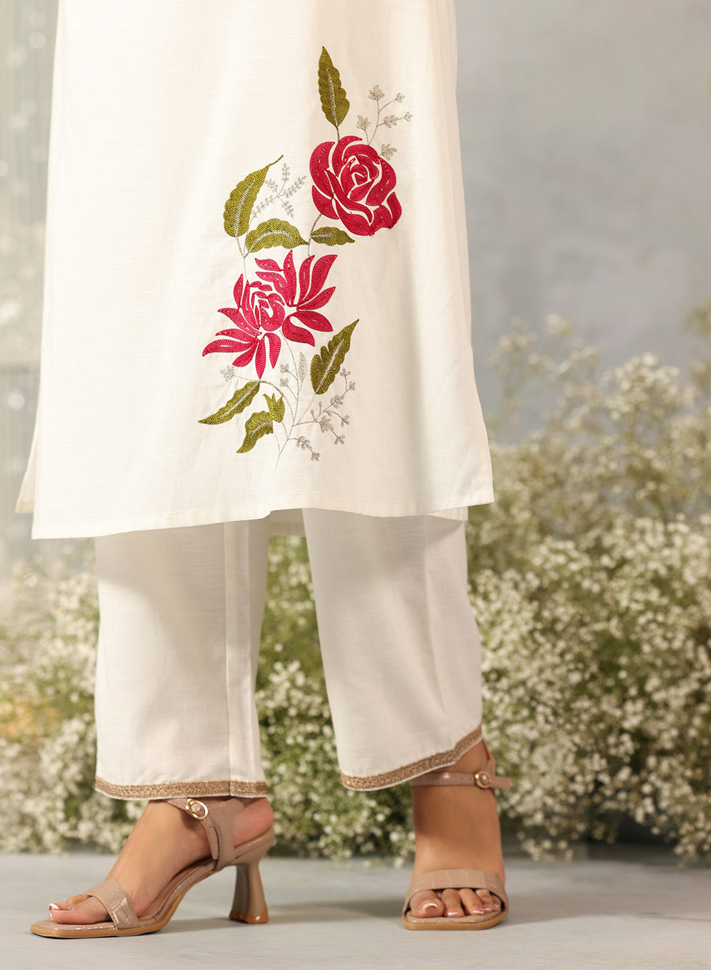 Waist-down view of Ulfat Pearl Ivory Kurta with pink rose motif on edge and zari-detailed hem of solid cotton linen pants.