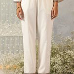 Front view of pearl ivory cotton linen straight pants with zari-trimmed hem and soft, structured mid-rise silhouette.