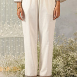 Front view of pearl ivory cotton linen straight pants with zari-trimmed hem and soft, structured mid-rise silhouette.