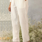 Close-up side shot of Ulfat set's ivory straight pants showcasing clean lines, slit pockets, and subtle zari hem detailing.